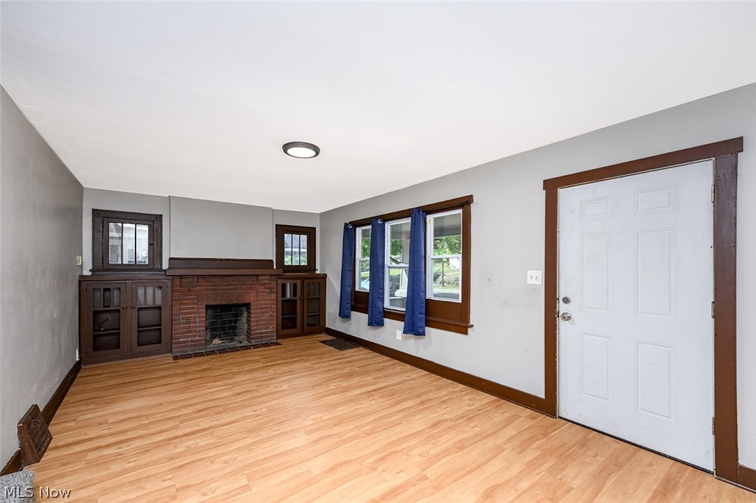 1313 Manchester Road Akron, OH 44307 - Photo 16 of 28 Wood-finish flooring, brick fireplace, built-in cabinetry, multiple windows, and a flush-mount ceiling light