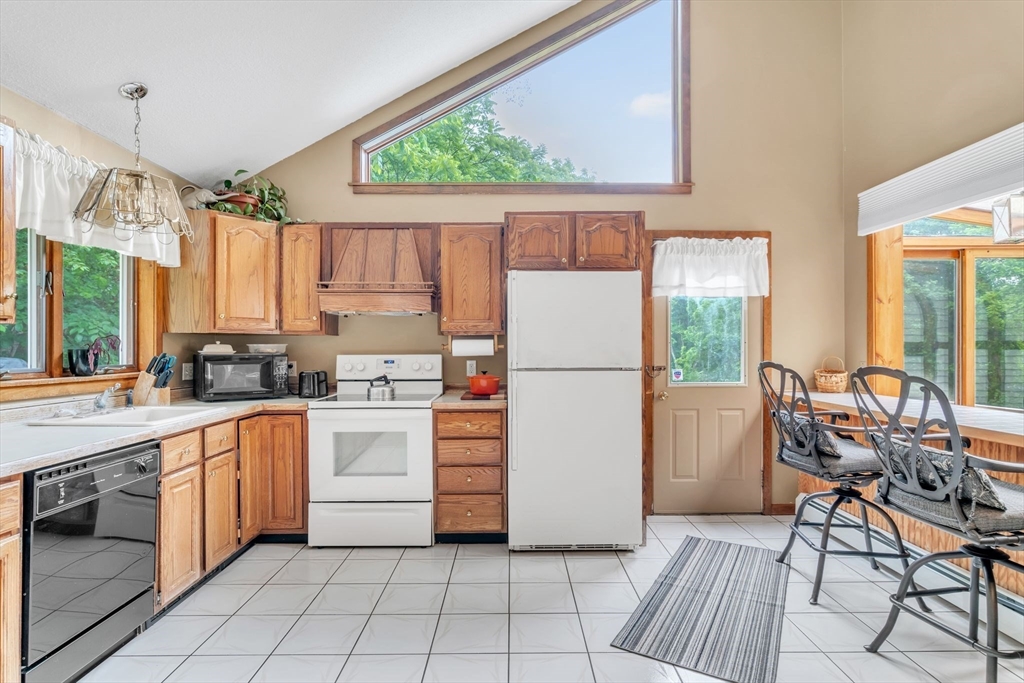 81 Munn Road Monson, MA 01057 - Photo 16 of 42 a kitchen with a refrigerator a stove a sink and a dining table with wooden cabinet