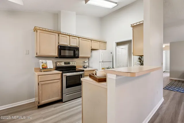 a kitchen with a stove a refrigerator and chairs