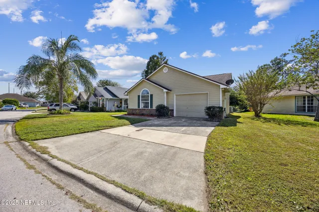 a front view of a house with a yard and potted plants