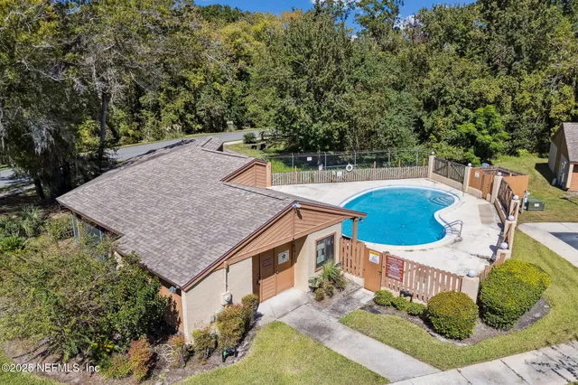an aerial view of a house with swimming pool and large trees