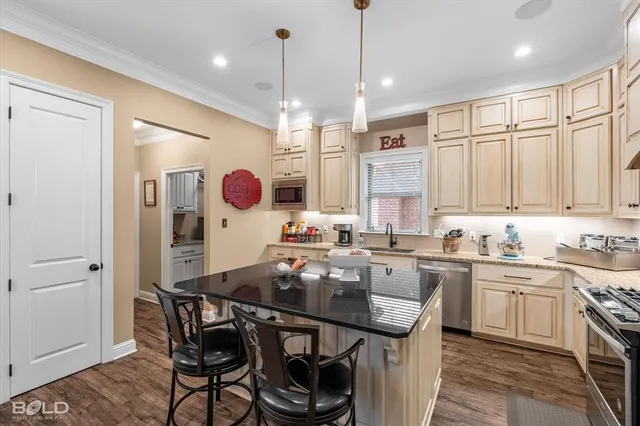 a kitchen with stainless steel appliances granite countertop a sink a stove a dining table and chairs
