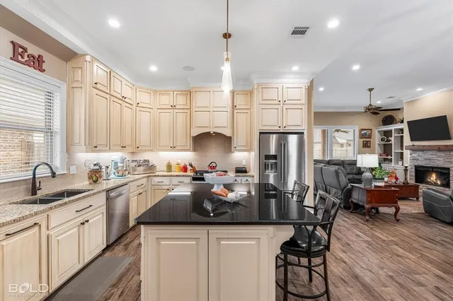 a kitchen with stainless steel appliances granite countertop a refrigerator a sink dishwasher a dining table and chairs with wooden floor