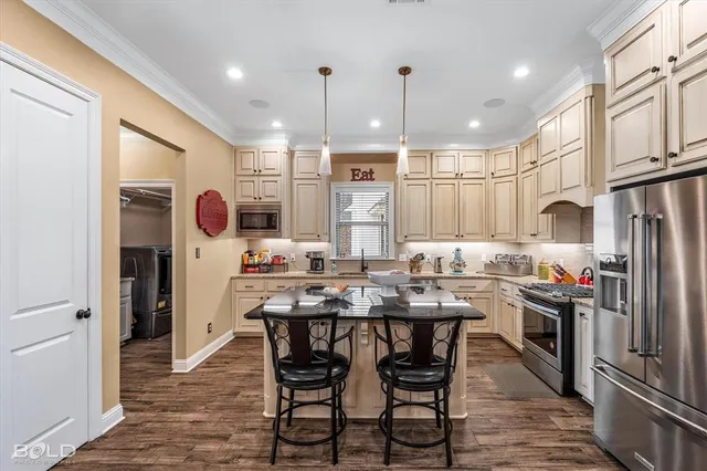 a kitchen with stainless steel appliances kitchen island granite countertop a stove a refrigerator cabinets a dining table and chairs