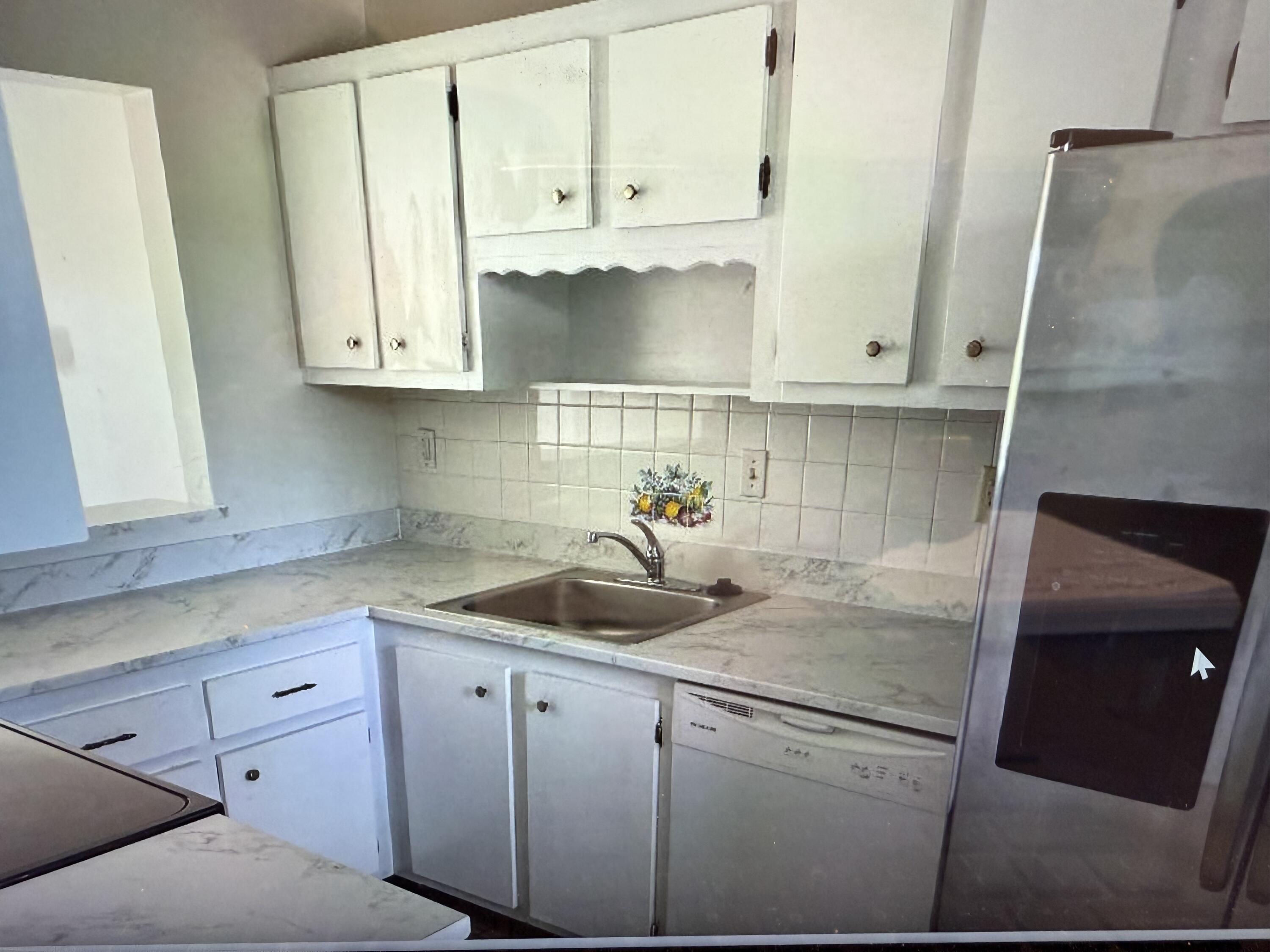 5403 Southeast Miles Grant Road Stuart, FL 34997 - Photo 2 of 5 a kitchen with white cabinets and sink