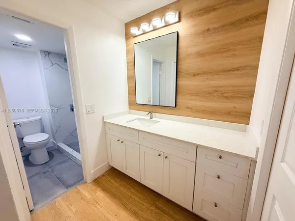 a bathroom with a granite countertop sink mirror and toilet