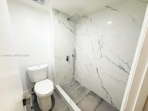 a bathroom with a granite countertop toilet and a shower