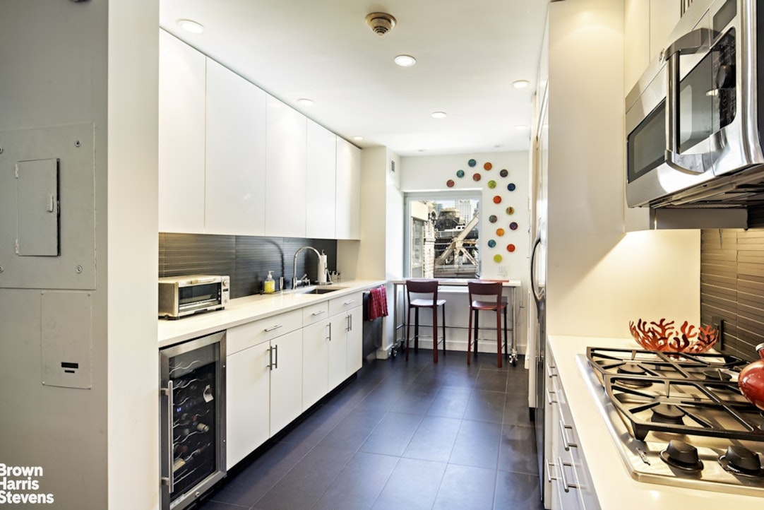 425 East 58th Street, Unit 7D Manhattan, NY 10022 - Photo 6 of 13 a kitchen with stainless steel appliances a stove a sink and a refrigerator