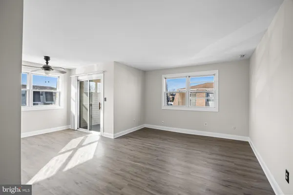 an empty room with wooden floor and windows