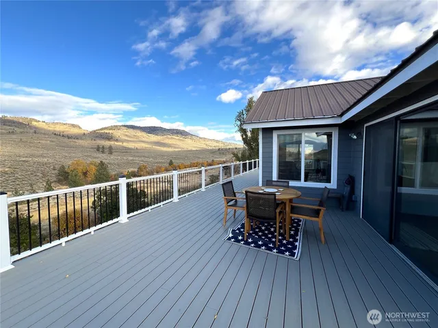 a view of a roof deck with table and chairs a barbeque with wooden floor and fence