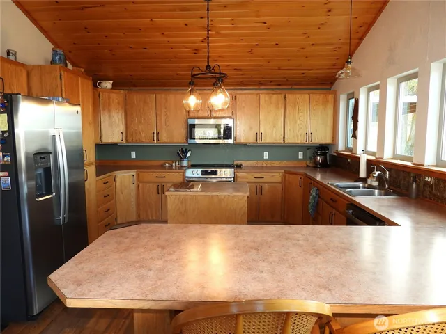 a kitchen with stainless steel appliances granite countertop a sink a stove and a refrigerator