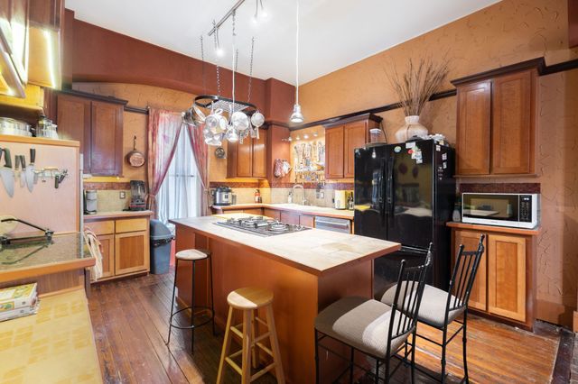 a kitchen with stainless steel appliances kitchen island granite countertop a table chairs and a refrigerator