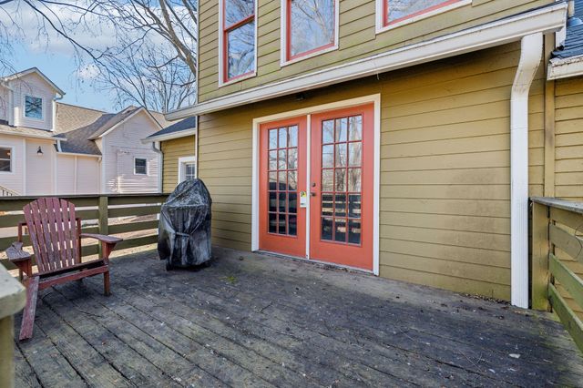 a view of a house with a barbeque and wooden bench
