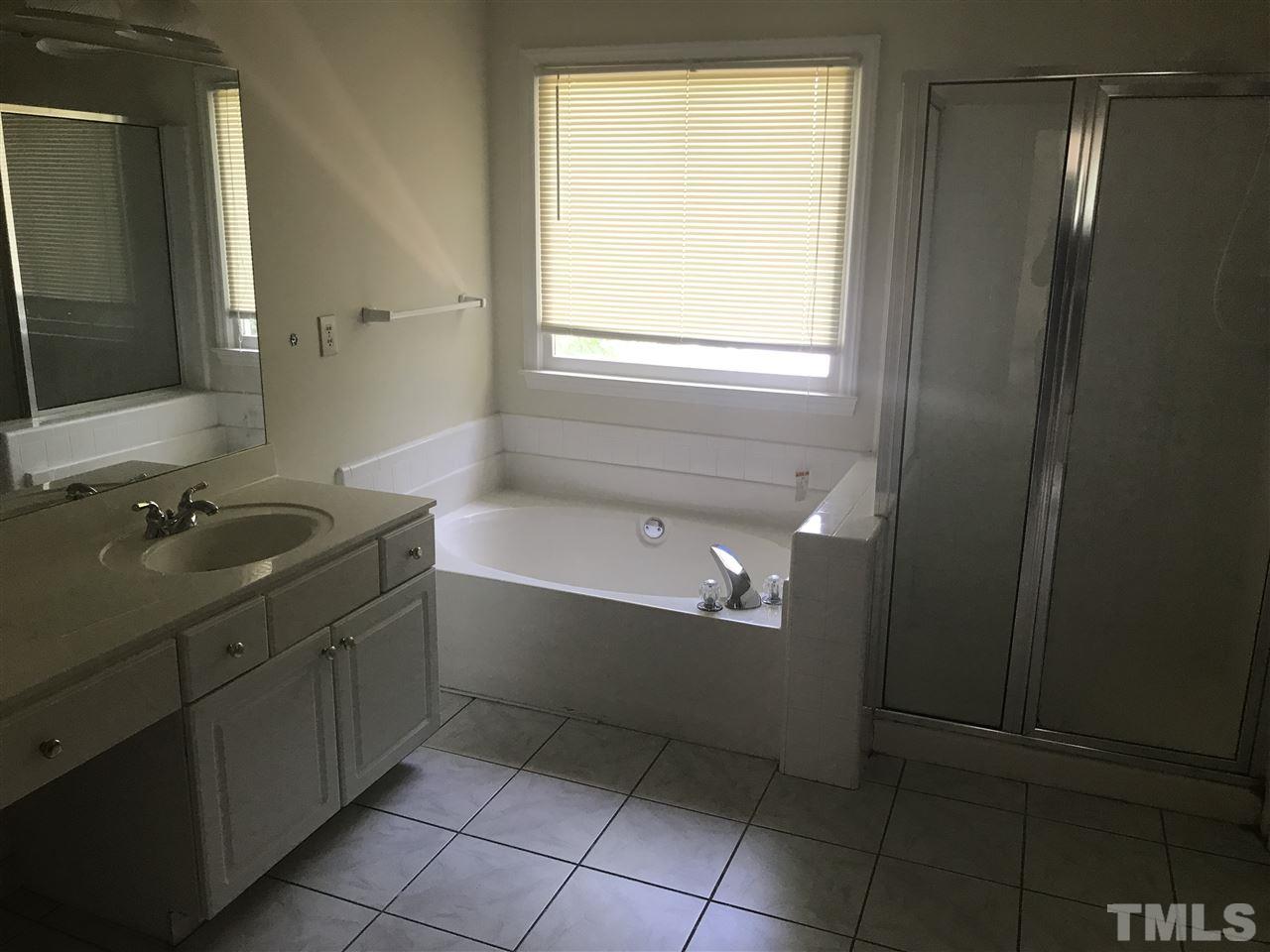 3205 Coppedge Lane Raleigh, NC 27616 - Photo 13 of 20 a bathroom with a bathtub sink vanity and mirror