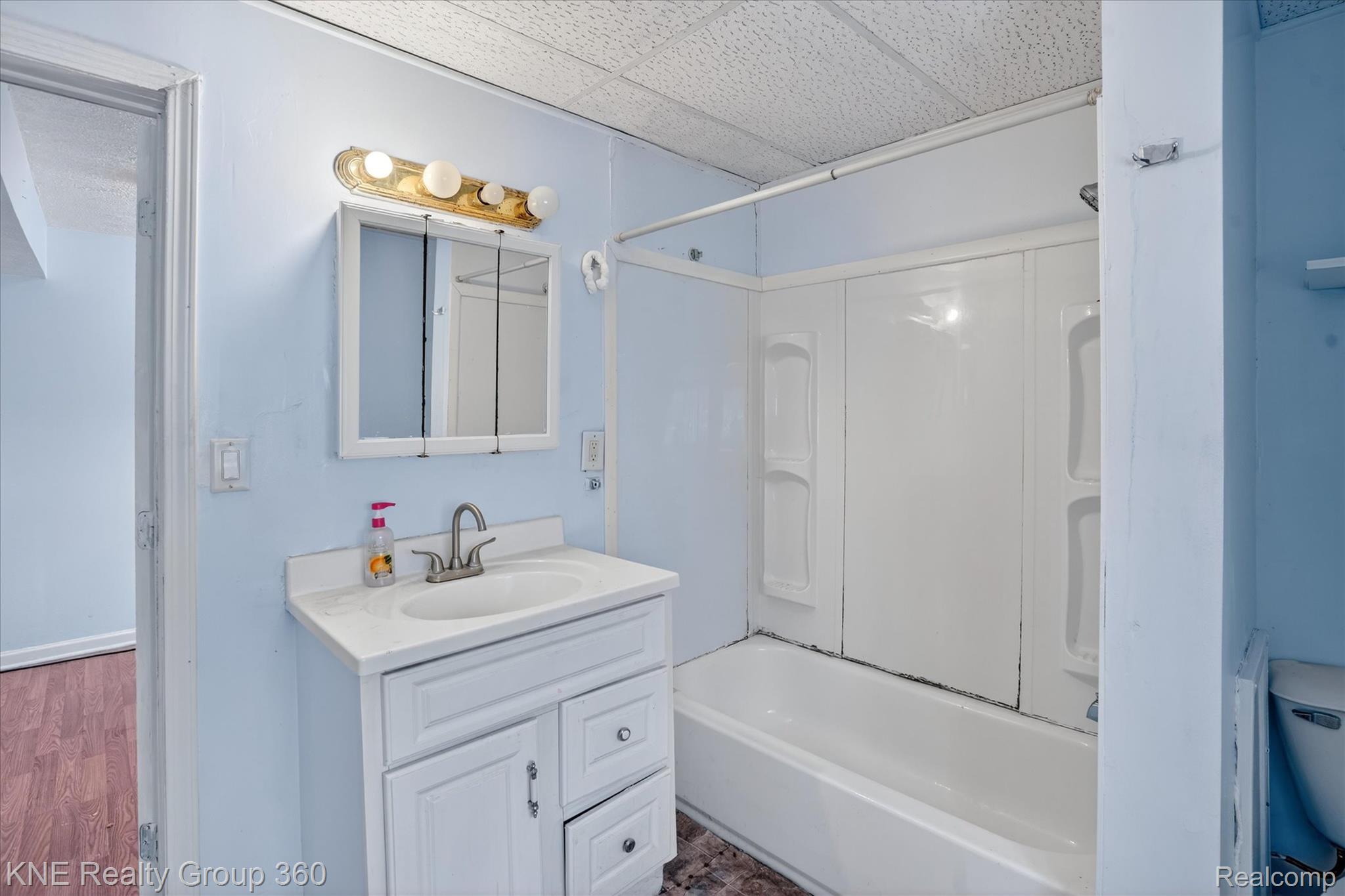 4928 Hughes Road Lansing, MI 48910 - Photo 21 of 35 Full bath featuring vanity, shower / bath combination, a drop ceiling, and wood finished floors