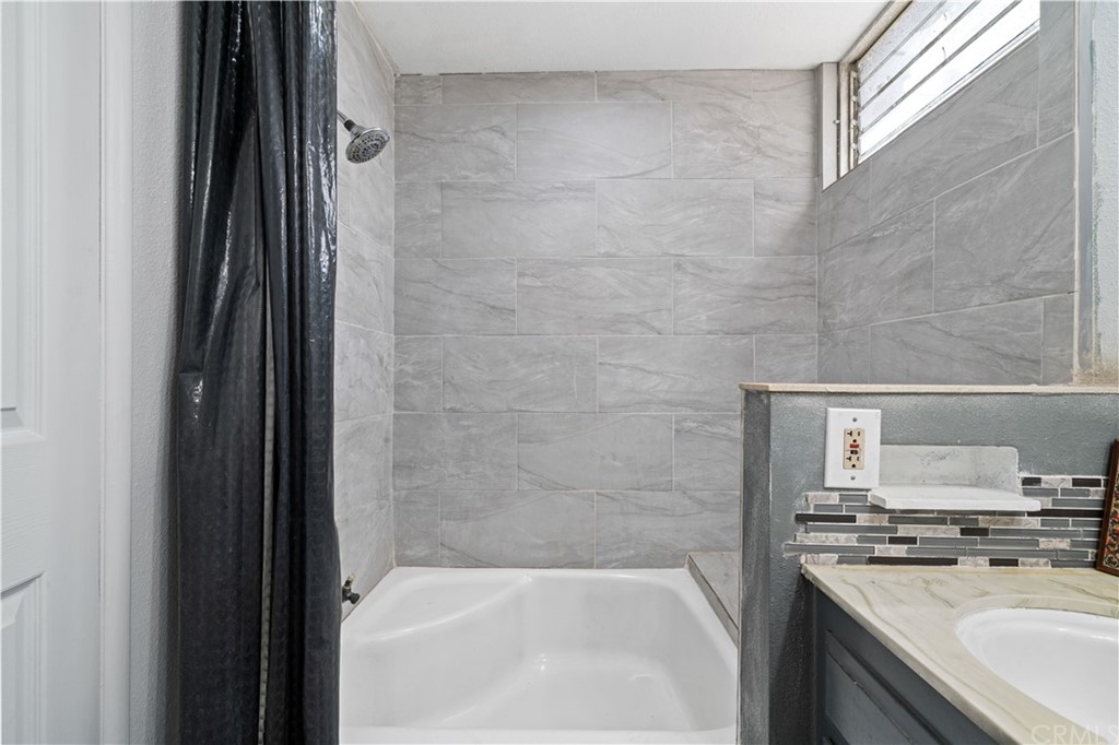4909 El Molino Avenue Riverside, CA 92504 - Photo 25 of 33 a bathroom with a granite countertop sink a mirror and a bathtub