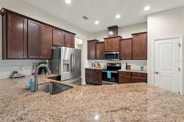 a kitchen with granite countertop wooden cabinets a refrigerator and a stove top oven