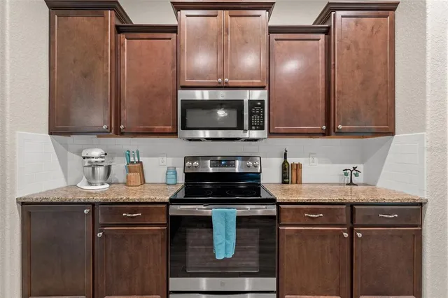 a kitchen with kitchen island granite countertop a sink stove and microwave
