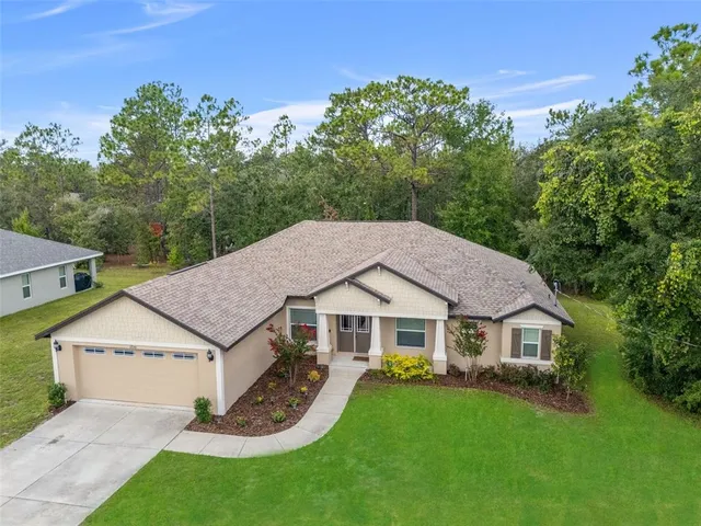 a aerial view of a house next to a big yard and large trees