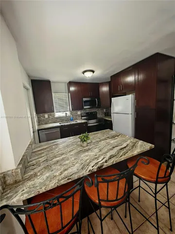 a kitchen with stainless steel appliances kitchen island a refrigerator sink and wooden cabinets