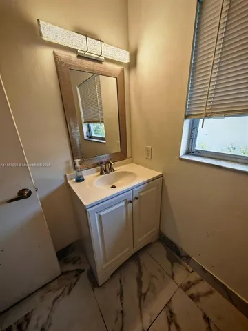 a utility room with a sink a mirror and cabinets