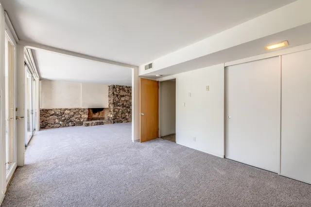 a backyard of a house with table and chairs under an umbrella