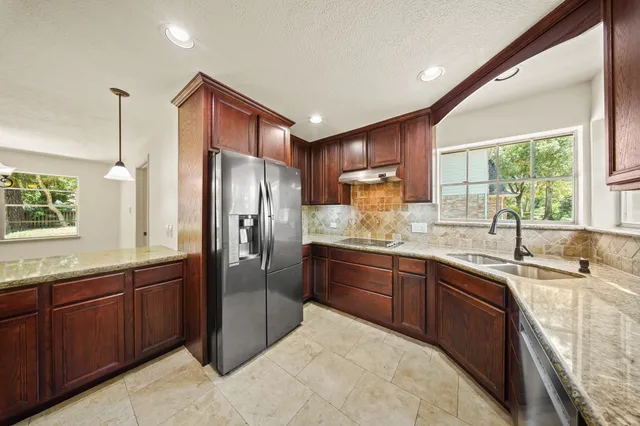 a kitchen with stainless steel appliances granite countertop a sink refrigerator and window