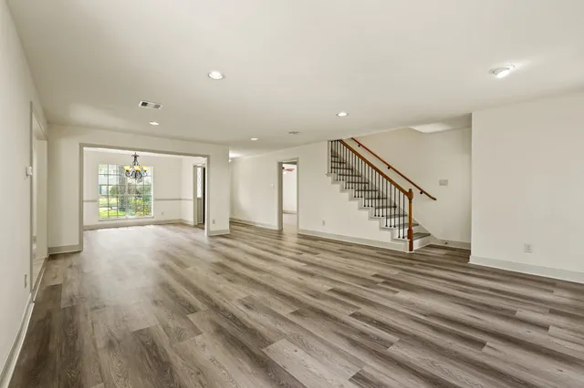 a view of an empty room with wooden floor and stairs