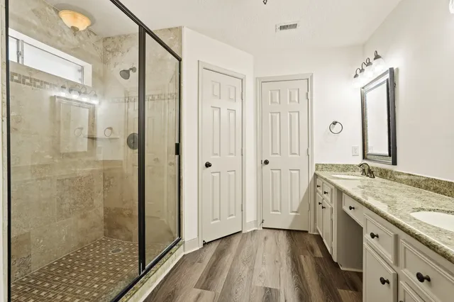 a spacious bathroom with a granite countertop sink a mirror a shower and a bathtub