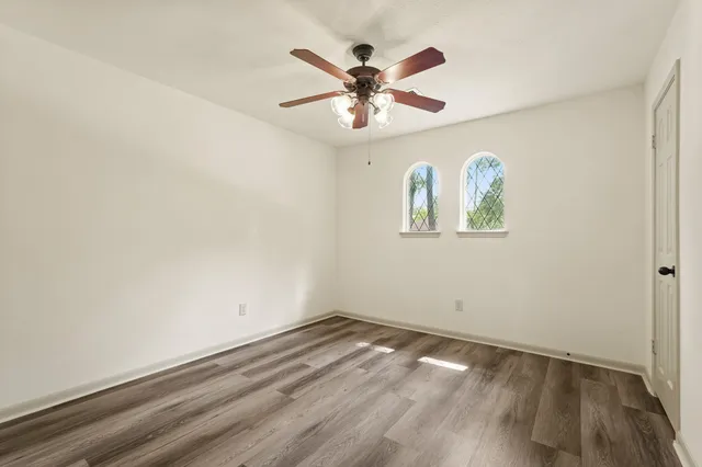 an empty room with ceiling fan and wooden floor