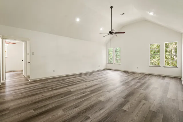 an empty room with wooden floor windows and ceiling fan