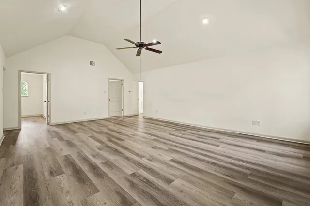 a view of empty room with wooden floor and ceiling fan