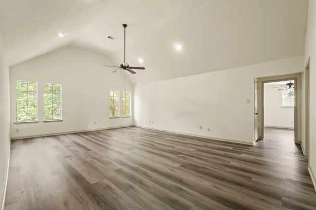 an empty room with wooden floor cabinet and windows