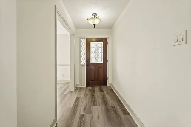 a view of a hallway with wooden floor and a bathroom