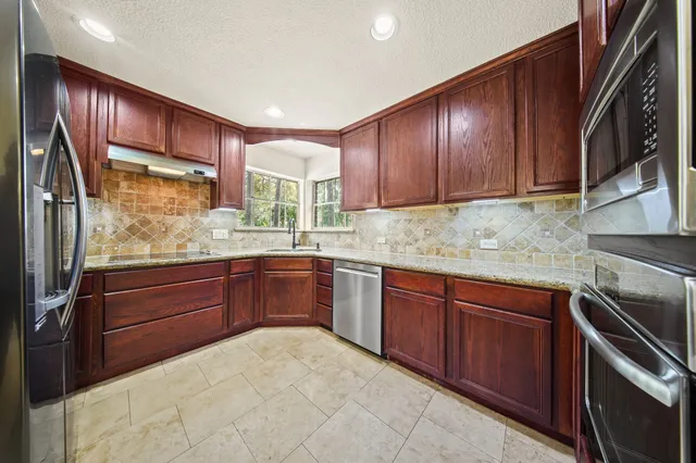a kitchen with stainless steel appliances granite countertop wooden cabinets a stove top oven a sink and dishwasher