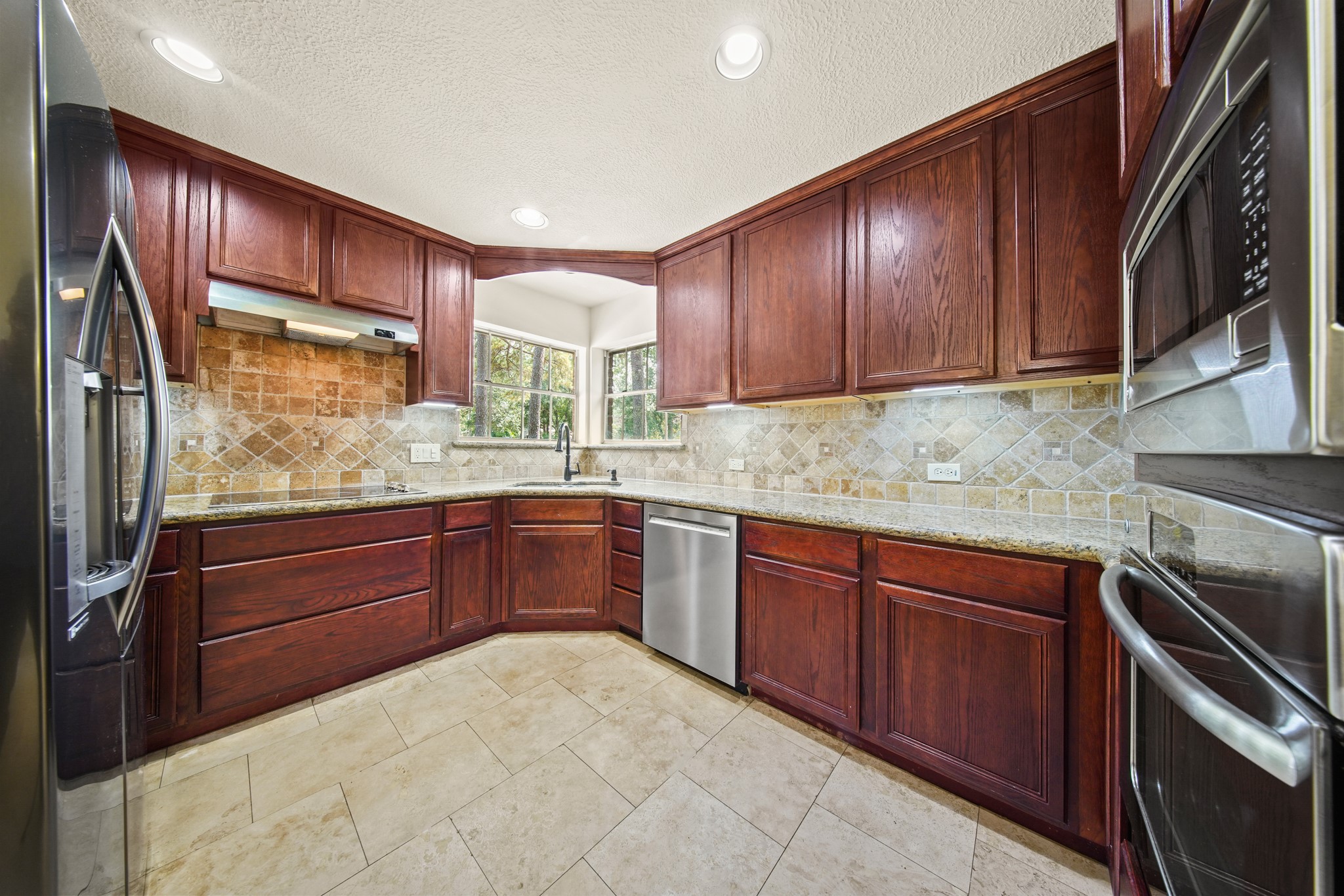 17606 Rustington Drive Spring, TX 77379 - Photo 10 of 44 a kitchen with stainless steel appliances granite countertop wooden cabinets a stove top oven a sink and dishwasher