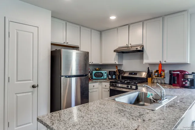 a kitchen with stainless steel appliances granite countertop a refrigerator sink and stove