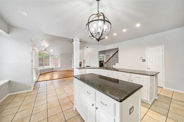a kitchen with a sink a chandelier stainless steel appliances cabinets and living room view