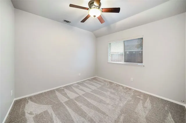 an empty room with chandelier fan and windows