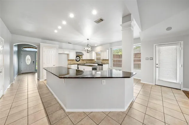 a large kitchen with kitchen island a large counter top and stainless steel appliances