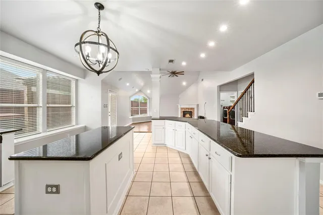 a large white kitchen with kitchen island granite countertop lots of counter space a sink and a large window