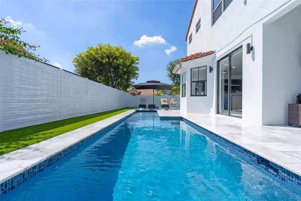 a view of a white house with a swimming pool and sitting area