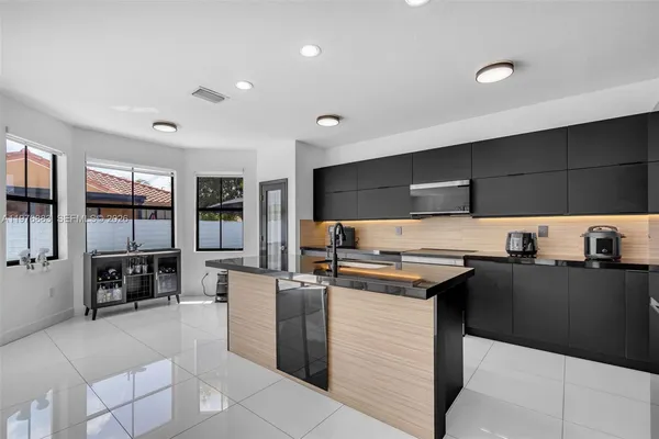 a kitchen with stainless steel appliances granite countertop a stove a sink dishwasher a dining table and chairs with wooden floor