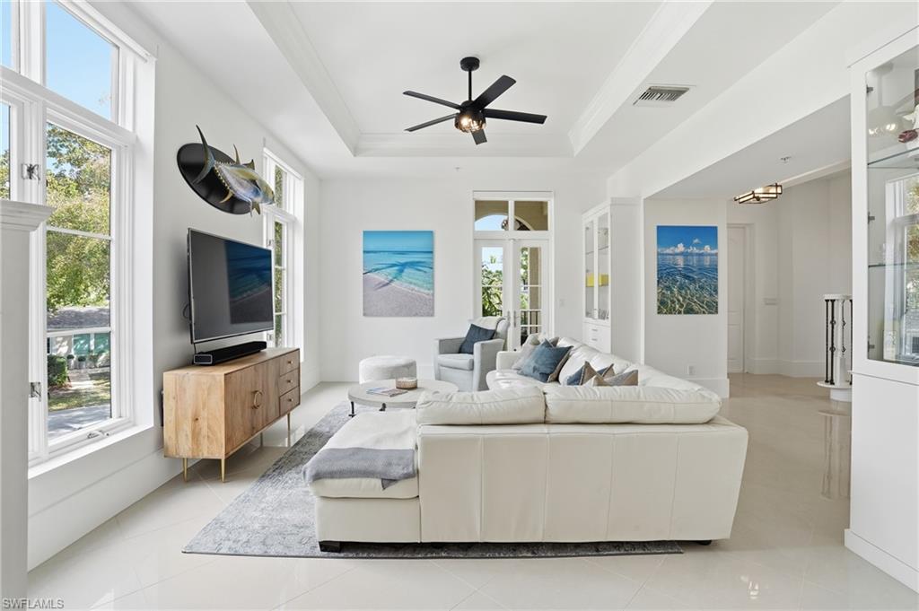 1008 7th Street South, Unit B1 Naples, FL 34102 - Photo 15 of 48 Living room featuring light tile patterned flooring, a ceiling fan, and a raised ceiling