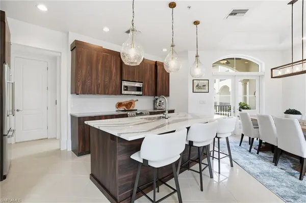 a kitchen with stainless steel appliances granite countertop a sink a window and chairs