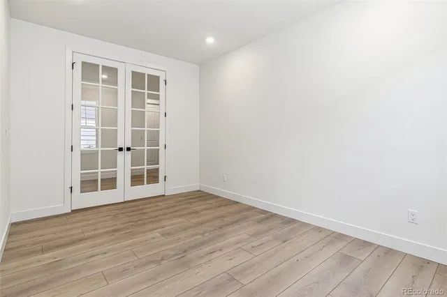 an empty room with wooden floor and windows