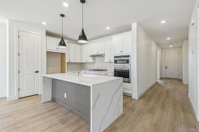 a kitchen with kitchen island a sink stainless steel appliances and wooden floor
