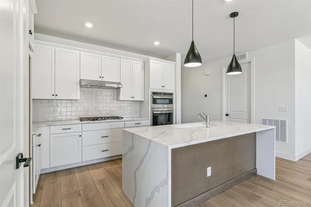 a kitchen with kitchen island sink stove and white cabinets