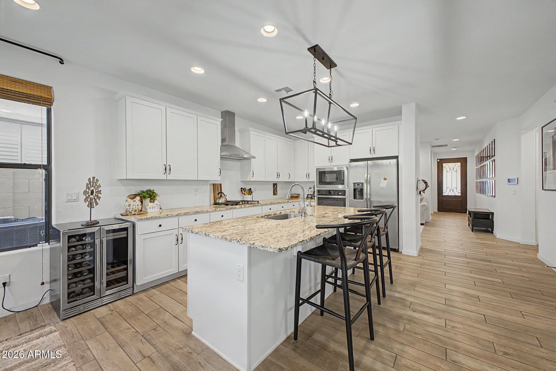 819 West Deer Creek Road Phoenix, AZ 85048 - Photo 26 of 76 a kitchen with stainless steel appliances kitchen island granite countertop a wooden floor and white cabinets