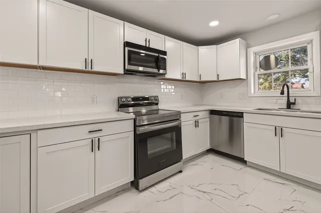 a kitchen with white cabinets stainless steel appliances and sink
